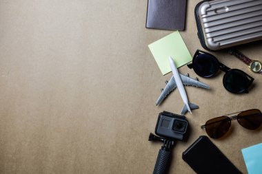 Kahverengi arka planda gezginler için kullanılan aksesuarların üst görünümü. Seyahat aksesuarları ve kopyalama alanı. Üst görünüm seyahat aksesuarları kavramı.