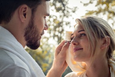 Genç adam kız arkadaşı için ter sildi. Birlikte şefkatle egzersiz yaptıktan sonra. Kavramsal çiftler parkta egzersiz yapıyor. Genç çiftler parkta egzersiz yaptıktan sonra ter siliyorlar..