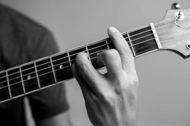 Erkekler gitar çalmayı öğreniyor. Yakın çekim müzisyenleri gitar akorlarını yakalıyor. Erkek müzisyenler akor tutar ve gitar çalar..