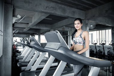 Spor salonundaki koşu makinesinde egzersiz yapan seksi Asyalı kadınlar. Spor salonunda çalışan sağlıklı bir kadın. Spor salonunda sağlık hizmeti ve egzersiz kavramı. Güzel kız spor salonunda spor yapıyor..
