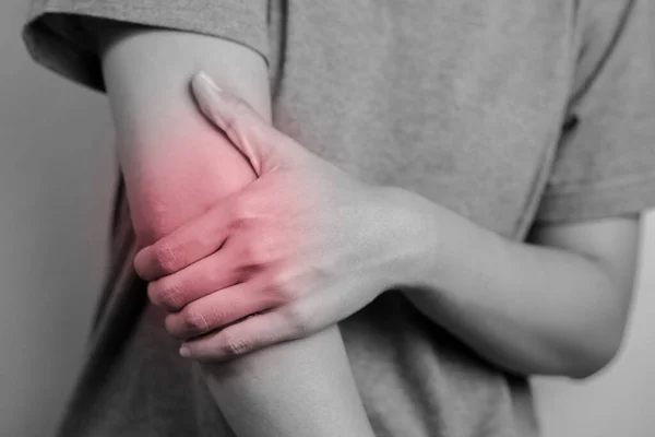 Women with pain in elbow. Acute pain in a elbow. Young woman holds on to elbow.