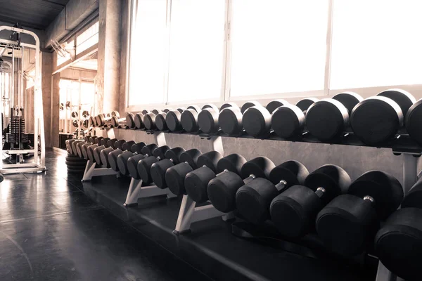 Dumbbells are on the shelves of the gym. Modern of gym interior with equipment. Sports equipment in the gym.