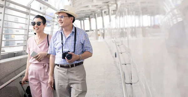 Casal Asiático Sênior Com Uma Mulher Arrastando Uma Mala Conversando — Fotografia de Stock