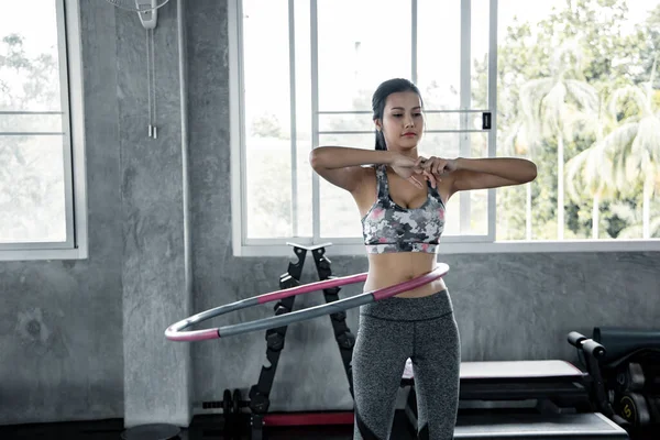 Asyalı seksi kadınlar spor salonunda hulahop oynayarak kardiyo egzersizi yapıyorlar. Spor salonunda sağlık hizmeti ve egzersiz kavramı. Güzel kız spor salonunda spor yapıyor..
