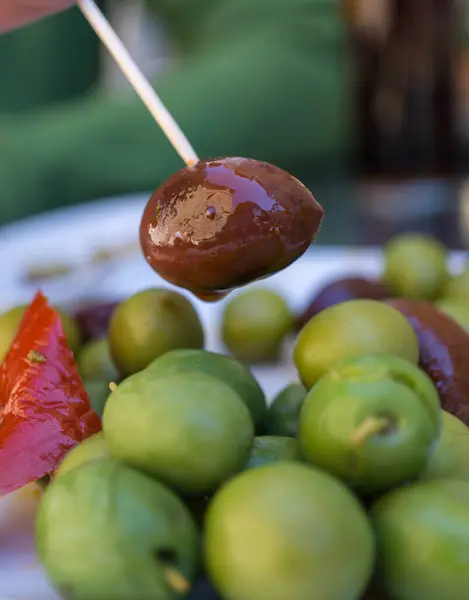 Baharatlı zeytin tabağındaki kürdanla bar masasında yakalanan siyah zeytin tipik İspanyol yeşili. — Stok fotoğraf