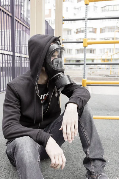 Un hombre solitario con una máscara respiratoria se sienta en un suelo en una ciudad desierta durante una epidemia de coronavirus en la hermosa primavera. Rusia, Samara, abril. Enfoque selectivo y suave . — Foto de Stock