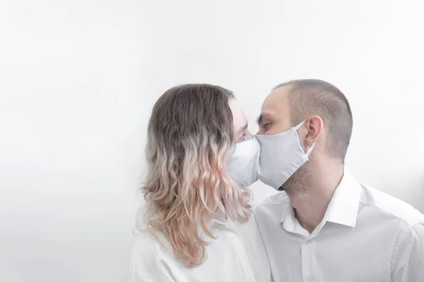 Erkek ve kadın tıbbi maskeli öpüşürler, virüse karşı korunurlar. Salgın. Coronavirüs.