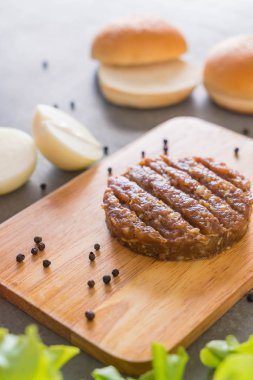 Hamburger malzemeleri ahşap tabakta dizilmiş.
