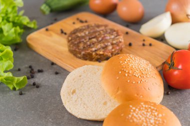 Hamburger malzemeleri ahşap tabakta dizilmiş.