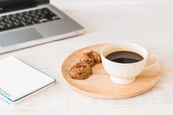 black coffee and cookies with laptop and note book