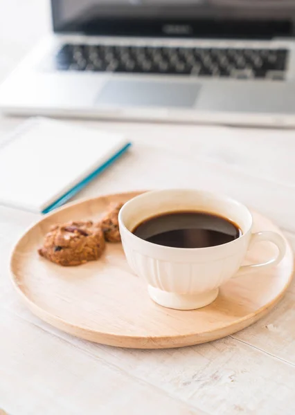 black coffee and cookies with laptop and note book