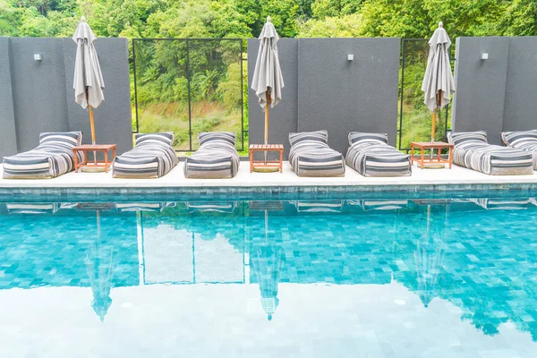 Vakker luksusparaply og stol rundt utendørs svømmebasseng – stockfoto