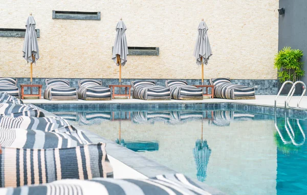 Belo guarda-chuva de luxo e cadeira em torno da piscina exterior — Fotografia de Stock