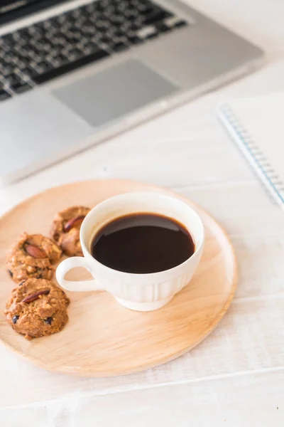 black coffee and cookies with laptop and note book