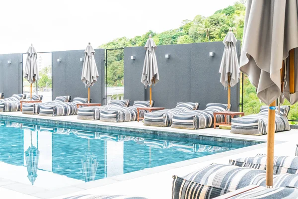 Hermoso paraguas de lujo y silla alrededor de la piscina al aire libre — Foto de Stock