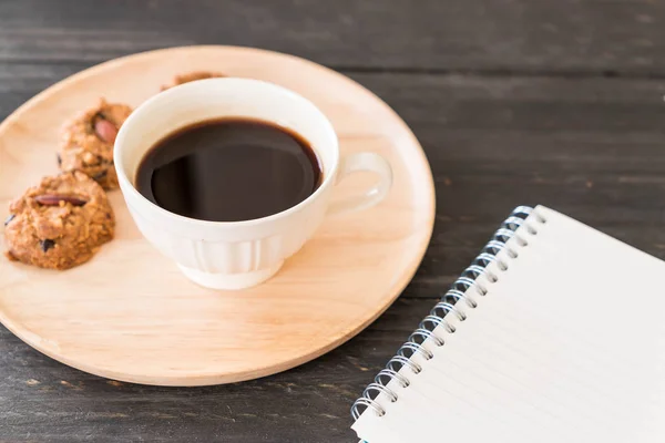 Schwarzer Kaffee und Kekse mit Laptop und Notizbuch — Stockfoto
