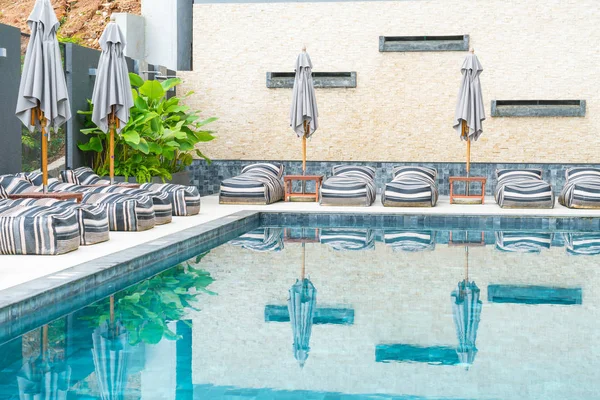 Hermoso paraguas de lujo y silla alrededor de la piscina al aire libre — Foto de Stock