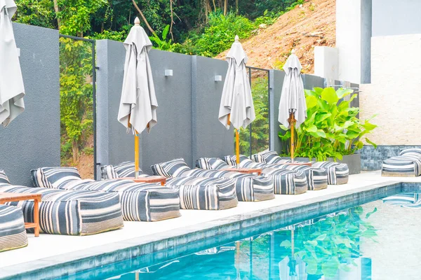 Belo guarda-chuva de luxo e cadeira em torno da piscina exterior — Fotografia de Stock