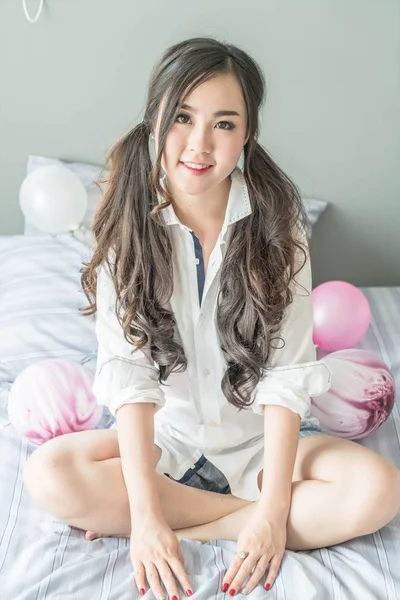 Encantadora mujer asiática sonriendo cara acostada en la cama —  Fotos de Stock