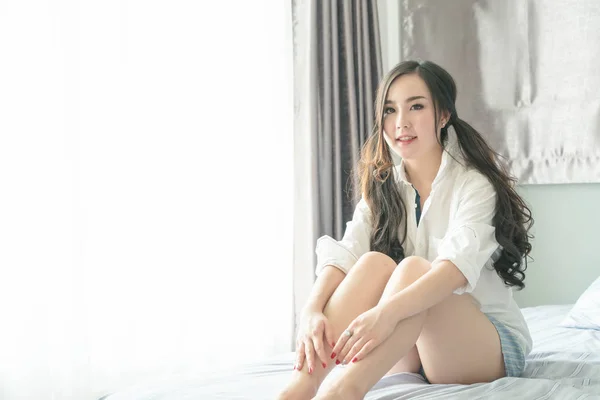 Encantadora mujer asiática sonriendo cara acostada en la cama —  Fotos de Stock