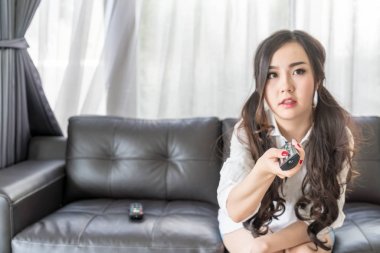 Genç Asyalı kadın evde oturma odasında TV kanalı değiştirme