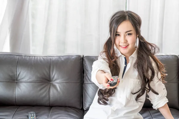 Молода азіатка змінює телевізійний канал вдома у вітальні — стокове фото