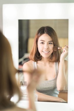 Genç güzel Asyalı ayna yakınındaki makyaj yapma kadın