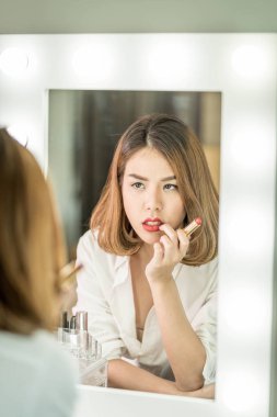 Genç güzel Asyalı ayna yakınındaki makyaj yapma kadın