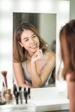 Genç güzel Asyalı ayna yakınındaki makyaj yapma kadın