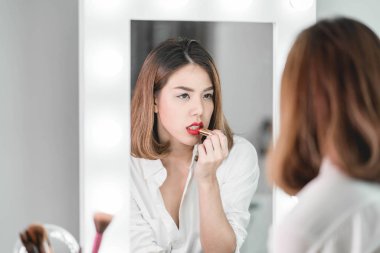 Genç güzel Asyalı ayna yakınındaki makyaj yapma kadın