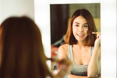 Genç güzel Asyalı ayna yakınındaki makyaj yapma kadın