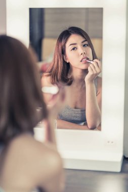 Genç güzel Asyalı ayna yakınındaki makyaj yapma kadın