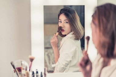 Genç güzel Asyalı ayna yakınındaki makyaj yapma kadın