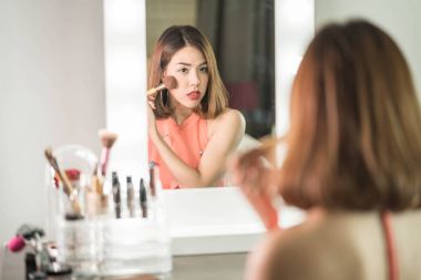 Genç güzel Asyalı ayna yakınındaki makyaj yapma kadın