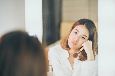 Genç güzel Asyalı ayna yakınındaki makyaj yapma kadın