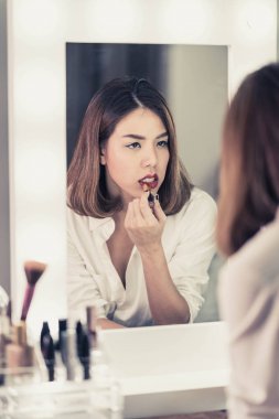 Genç güzel Asyalı ayna yakınındaki makyaj yapma kadın