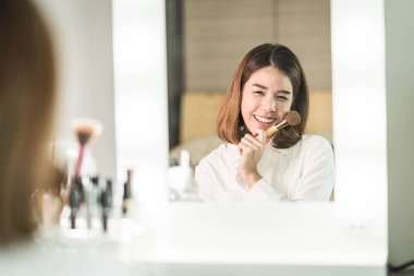 Genç güzel Asyalı ayna yakınındaki makyaj yapma kadın