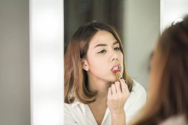 Genç güzel Asyalı ayna yakınındaki makyaj yapma kadın