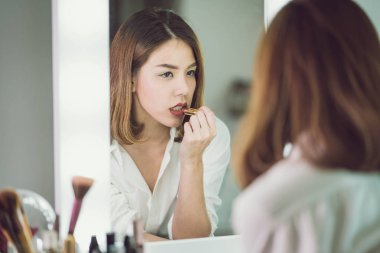 Genç güzel Asyalı ayna yakınındaki makyaj yapma kadın