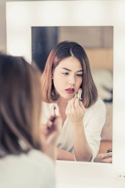 Genç güzel Asyalı ayna yakınındaki makyaj yapma kadın