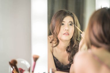 Genç güzel Asyalı ayna yakınındaki makyaj yapma kadın