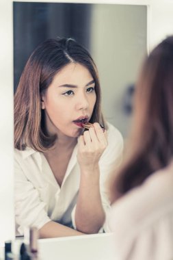 Genç güzel Asyalı ayna yakınındaki makyaj yapma kadın