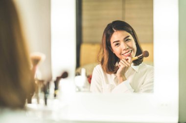 Genç güzel Asyalı ayna yakınındaki makyaj yapma kadın