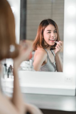 Genç güzel Asyalı ayna yakınındaki makyaj yapma kadın