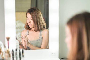 Genç güzel Asyalı ayna yakınındaki makyaj yapma kadın