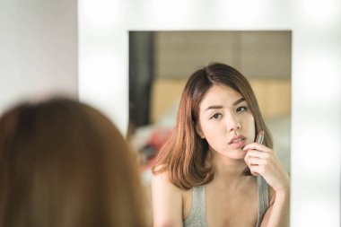 Genç güzel Asyalı ayna yakınındaki makyaj yapma kadın