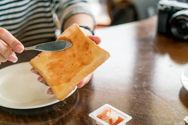 Mão segurando pão e geléia de morango fazendo para o café da manhã — Fotografia de Stock
