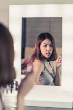 Genç güzel Asyalı ayna yakınındaki makyaj yapma kadın
