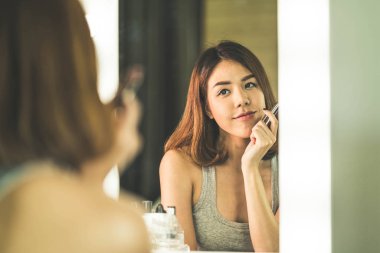 Genç güzel Asyalı ayna yakınındaki makyaj yapma kadın