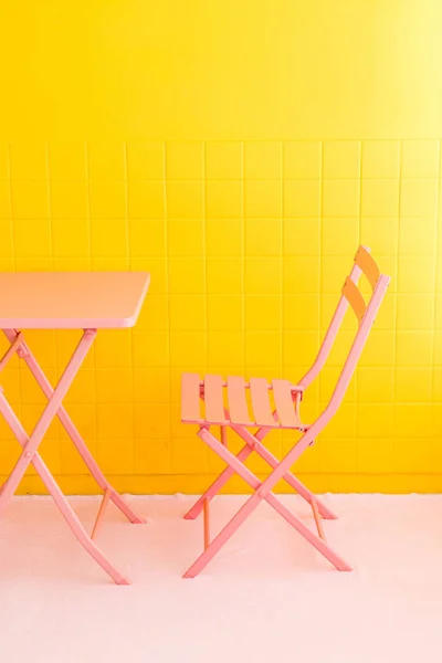 Leerer rosa Stuhl und Tisch mit gelber Wand — Stockfoto